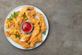 Breaded chicken strips with tomato ketchup on a white plate. Fast food on dark brown background. Top view with copy space Royalty Free Stock Photo