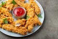 Breaded chicken strips with tomato ketchup on a white plate. Fast food on dark brown background. Top view with copy space Royalty Free Stock Photo