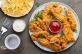 Breaded chicken strips with two kinds of sauces, fried potatoes and beer on a wooden Board. Fast food on dark brown background. To Royalty Free Stock Photo