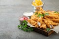 Breaded chicken strips with two kinds of sauces and fried potatoes on a wooden Board. Fast food on dark brown background. with cop Royalty Free Stock Photo