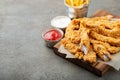 Breaded chicken strips with two kinds of sauces and fried potatoes on a wooden Board. Fast food on dark brown background. with cop Royalty Free Stock Photo