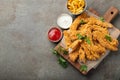 Breaded chicken strips with two kinds of sauces and fried potatoes on a wooden Board. Fast food on dark brown background. Top view Royalty Free Stock Photo