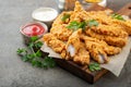 Breaded chicken strips with two kinds of sauces on a wooden Board. Fast food on dark brown background