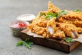 Breaded chicken strips with two kinds of sauces on a wooden Board. Fast food on dark brown background