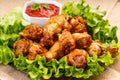 Breaded chicken wings.Fried breaded chicken wings with lettuce and tomatoes with ketchup on a wooden background. fast food, close- Royalty Free Stock Photo