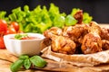 Breaded chicken wings.Fried breaded chicken wings with lettuce and tomatoes on wooden background close up Royalty Free Stock Photo