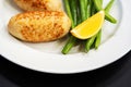 Breaded cutlet with green beans and lemon on a white plate. Close-up Royalty Free Stock Photo