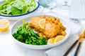Breaded fisch fillet with spicy baked potatoes and broccoli bimi salad