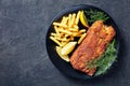 Breaded hake fillet served on a black plate