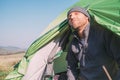 Breaded man traveler look out fronm tent and enjoy with sun light. Deep autumn or summer camping tourism