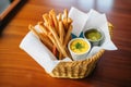 breadsticks in a napkin-lined basket with dips on the side Royalty Free Stock Photo