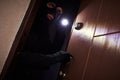 Break-in of an apartment. Thief in mask with flashlight