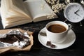 A break for a cup of coffee with chocolate in the company of your favorite book on a black wooden table - happy moments