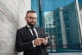 Break from job. Smiling mature businessman in formal clothes using smartphone and listening music near office building Royalty Free Stock Photo