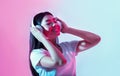 Break for music. Joyful asian girl with headphones dancing in neon Royalty Free Stock Photo