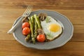 Breakfast with asparagus, fried egg and cherry tomatoes. Wooden table. Royalty Free Stock Photo