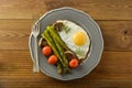 Breakfast with asparagus, fried egg and cherry tomatoes. Wooden table Royalty Free Stock Photo