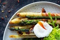 Breakfast of baked asparagus in spices with bacon, poached egg and crispy salad.