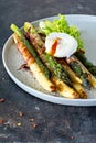 Breakfast of baked asparagus in spices with bacon, poached egg and crispy salad. Royalty Free Stock Photo