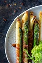 Breakfast of baked asparagus in spices with bacon, poached egg and crispy salad.