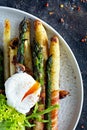 Breakfast of baked asparagus in spices with bacon, poached egg and crispy salad. Royalty Free Stock Photo