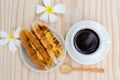 Breakfast with Baker Vietnamese or Viet Nam bread and black coffee with white plumeria flower on wooden retro background, top vi Royalty Free Stock Photo