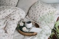 Breakfast in bed. Bedroom interior. Cup of coffee, rose flowers on porcelain plate. Wicker tray. Blank greeting card