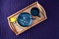 Breakfast in bed, black plate with scone crumbs and wood tray on a purple bedspread