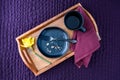 Breakfast in bed, black plate with scone crumbs and wood tray on a purple bedspread