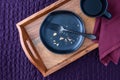 Breakfast in bed, black plate with scone crumbs and wood tray on a purple bedspread