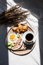 Breakfast in Bed Coffee Cup, Fried Egg, Bacon and Croissants on Wooden Tray. Trendy still life with interesting shadow.