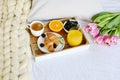 Breakfast in bed, croissant, coffee cup, berries, orange juice, pink tulips Royalty Free Stock Photo