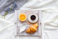 Breakfast in bed with croissant, coffee in cup with milk on tray on white bed background top view Royalty Free Stock Photo