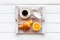 Breakfast in bed with croissant, coffee in cup with milk on tray on white wooden background top view Royalty Free Stock Photo