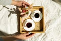 Breakfast in bed, female hands put try with two cups coffee and flower in sunlight Royalty Free Stock Photo