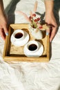 Breakfast in bed, female hands put try with two cups coffee and flower in sunlight Royalty Free Stock Photo