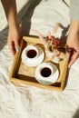 Breakfast in bed, female hands put try with two cups coffee and flower in sunlight Royalty Free Stock Photo