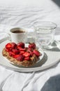 Breakfast in bed with morning sunlight. Elegant tray with toast and fresh strawberries, coffee and morning glass of water laying o Royalty Free Stock Photo