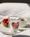 Breakfast in bed with morning sunlight. Elegant tray with toast and fresh strawberries, coffee and morning glass of water laying o