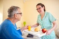 Breakfast in bed, residential care in a nursing home, elder man nursing home occupant being served breakfast by a nurse