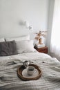Breakfast in bed scene. Cup of coffee, silver milk pitcher on wicker tray and linen blanket. Blurred pillows, night