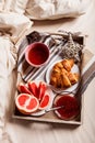 Breakfast in bed: tea with lemon, croissant with jam and grapefruit pieces