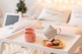 Breakfast in bed, tray with cup of coffee and macaroon. Modern bedroom interior. Romantic morning surprise.