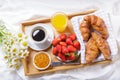 Breakfast in bed. Tray with cup of coffee , orange juice, fresh fruits and bunch of daisy flowers