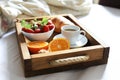 Breakfast in bed, a wooden tray of coffee, croissants, strawberry, orange close up. Honeymoon. Morning at the hotel.