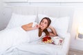 Breakfast in bed for young beautiful woman. Woman having breakfast in bed with fruits, coffee and biscuits. Morning waking up in Royalty Free Stock Photo