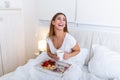 Breakfast in bed for young beautiful woman. Woman having breakfast in bed with fruits, coffee and biscuits. Morning waking up in Royalty Free Stock Photo