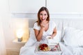 Breakfast in bed for young beautiful woman. Woman having coffee and breakfast in bed with fruits, coffee and biscuits. Morning Royalty Free Stock Photo