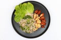 Breakfast in the black round plate on white floor. Rice vermicelli spicy salad with Fried Tofu, Fried chicken and lettuce