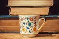 Breakfast of bookworm with vintage books and floral design cup of coffee. Selective focus Royalty Free Stock Photo